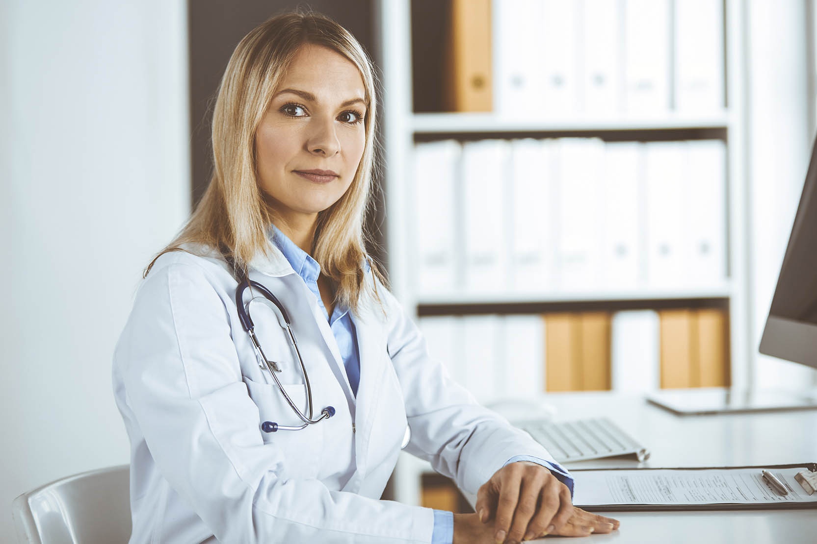 Friendly,Female,Doctor,Sitting,In,Clinic,At,Her,Working,Place.