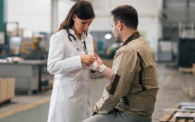 Female,Medic,Helping,Injured,Manual,Worker,At,Manufacturing,Plant.