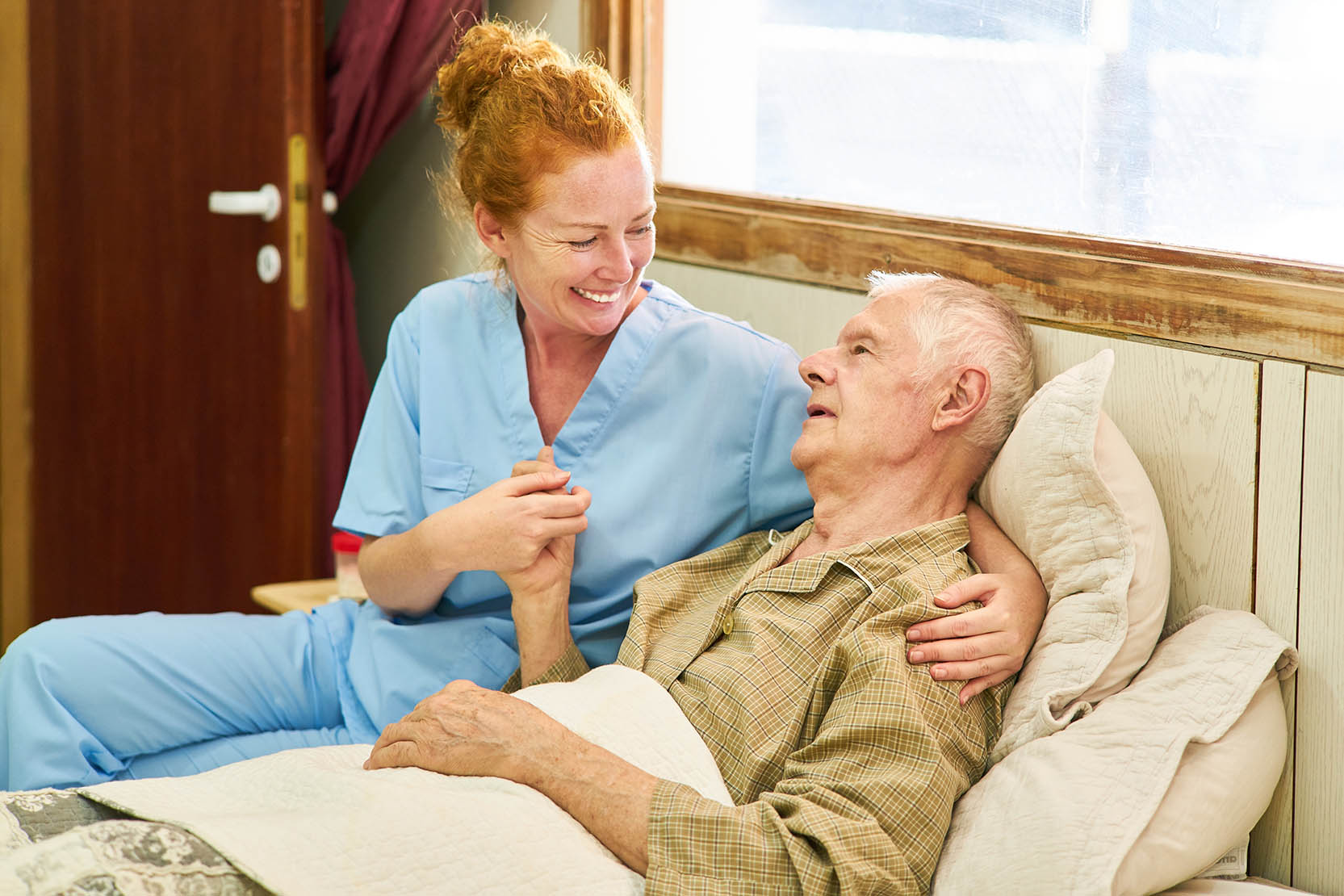 Nurse,At,The,Bed,Of,A,Sick,Senior,Holding,Hands