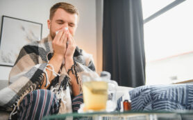 A,Sick,Man,Sits,At,Home,On,A,Gray,Sofa