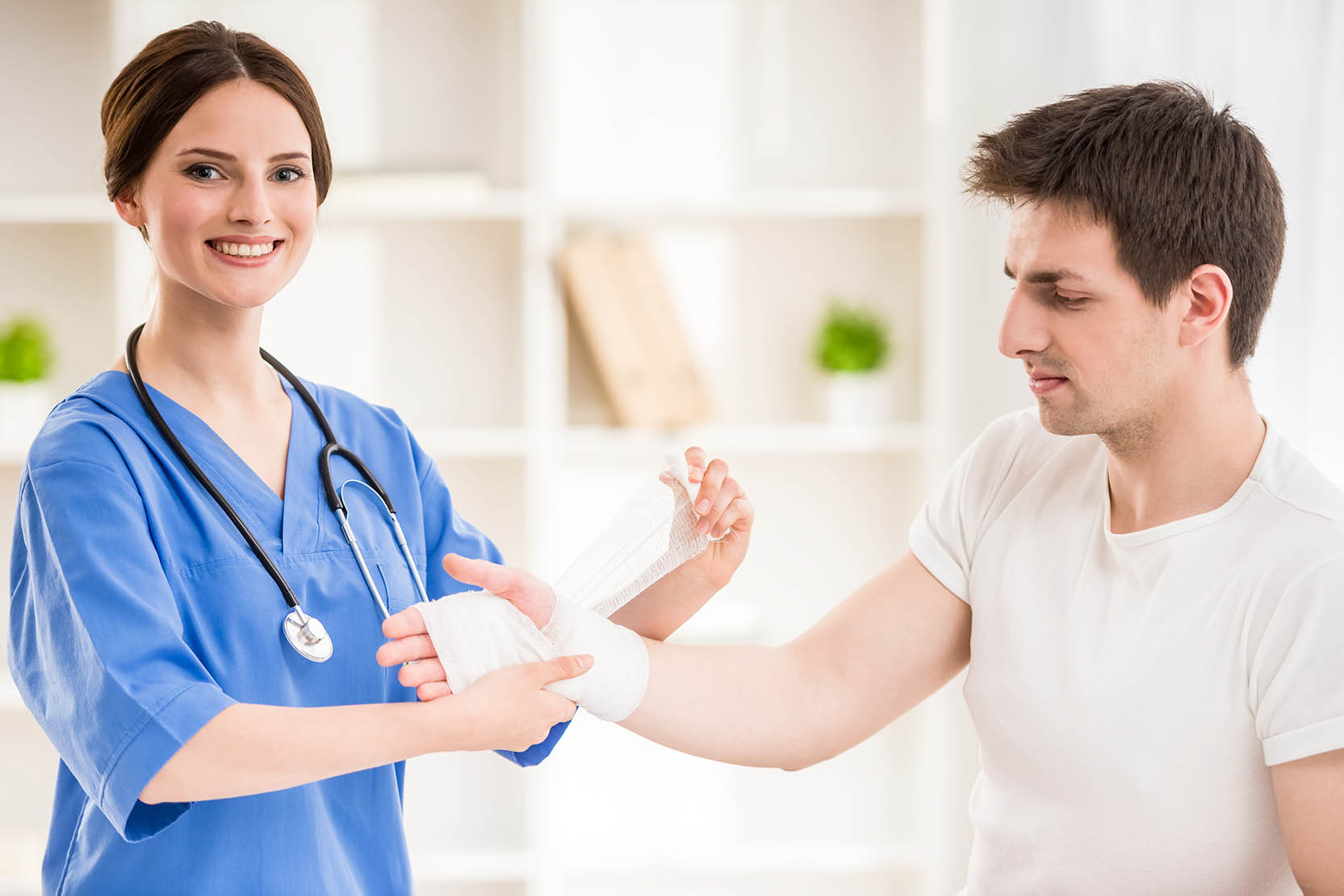 Young,Attractive,Female,Doctor,With,Stethoscope,Bandaging,Hand,Of,Male